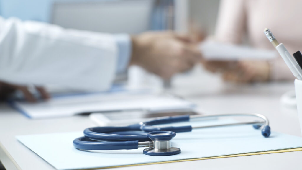 Professional doctor sitting at desk and giving a prescription to a patient