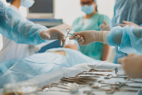 Assistant hands out instruments surgeon during surgery in the operating room